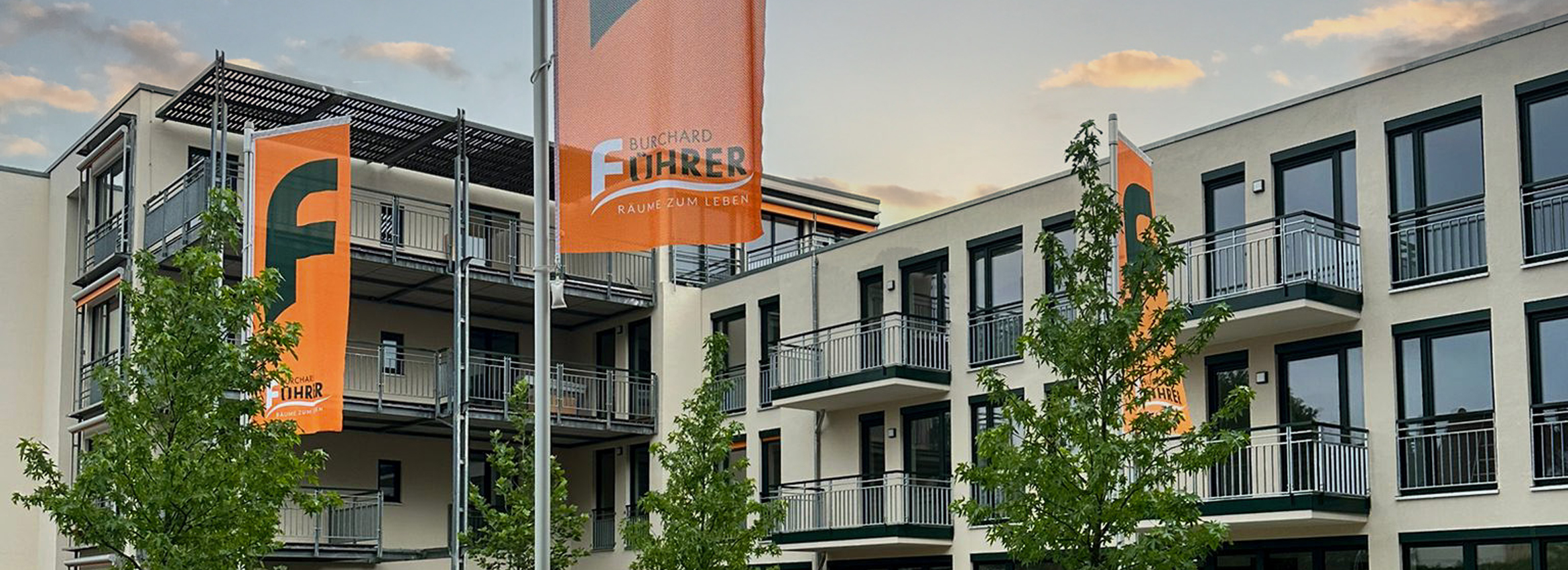 Titelbild der Startseite Eine Parklandschaft mit vielen Bäumen und einem Weg auf der linken Seite